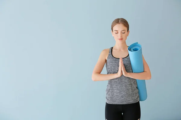 Young woman with yoga mat on color background — Stock Photo, Image