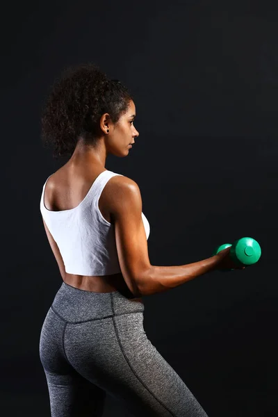 Sportieve Afro-Amerikaanse vrouw met halters op donkere achtergrond — Stockfoto