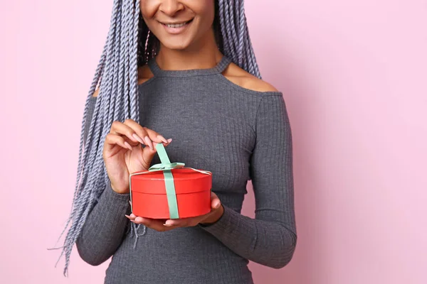Schöne afrikanisch-amerikanische Frau mit Geschenk auf farbigem Hintergrund — Stockfoto