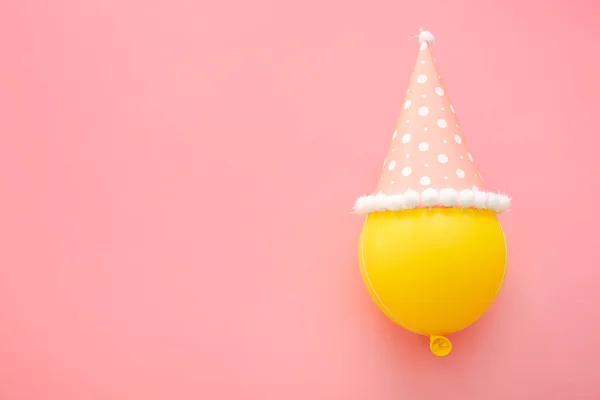 Balão com chapéu de festa no fundo da cor — Fotografia de Stock