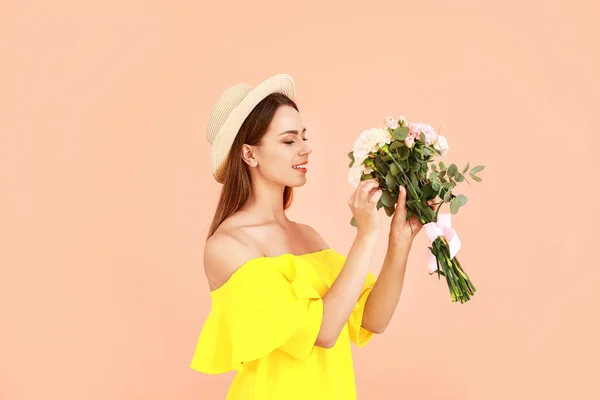 Mooie jonge vrouw met boeket van anjer bloemen op kleur achtergrond — Stockfoto