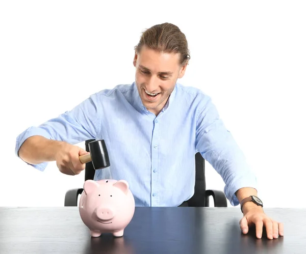 Bonito jovem que vai quebrar o banco porquinho na mesa contra o fundo branco — Fotografia de Stock