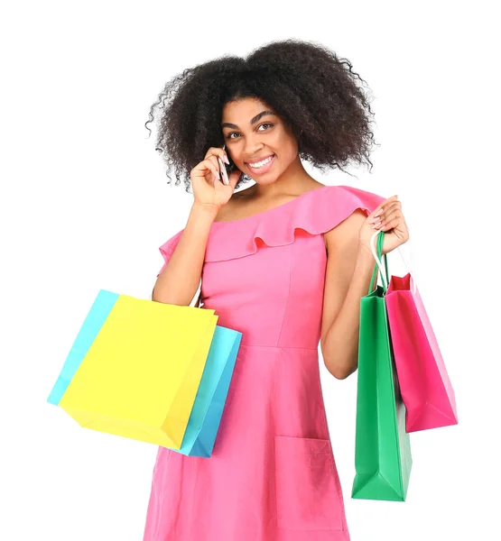 Krásná africko-americká žena s nákupními taškami telefonicky na bílém pozadí — Stock fotografie