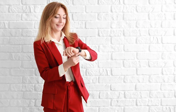 Portrait of stylish mature businesswoman looking at watch against white background — Stock Photo, Image