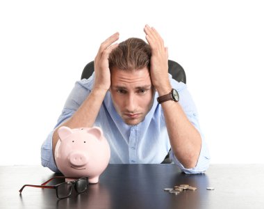 Depresyonda olan, kumbaralı genç adam beyaz arka planda masada oturuyor.