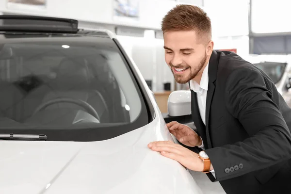 Happy male buyer near new car in salon — Stock Photo, Image