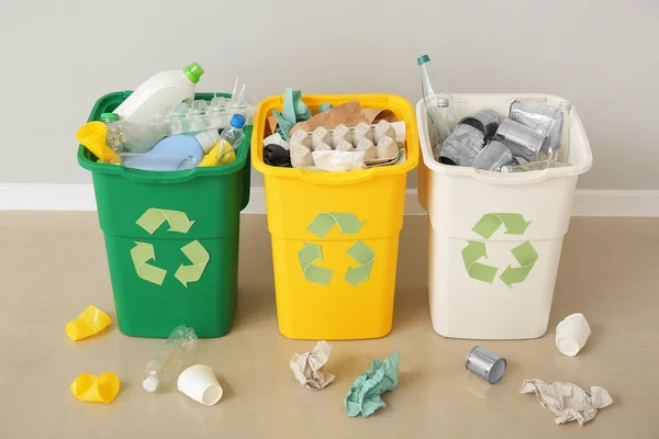 Containers with different types of garbage near light wall. Recycling concept — Stock Photo, Image