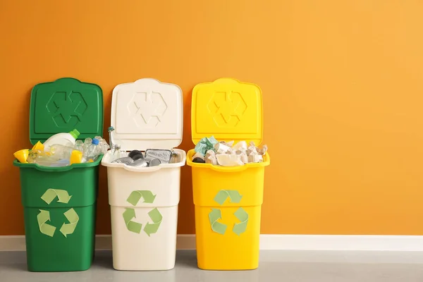 Containers with different types of garbage near color wall. Recycling concept — Stock Photo, Image