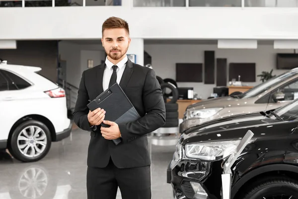 Salesman near car in modern salon — Stock Photo, Image