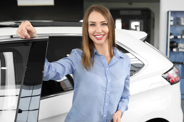 Comprador fêmea feliz perto de carro novo no salão — Fotografia de Stock