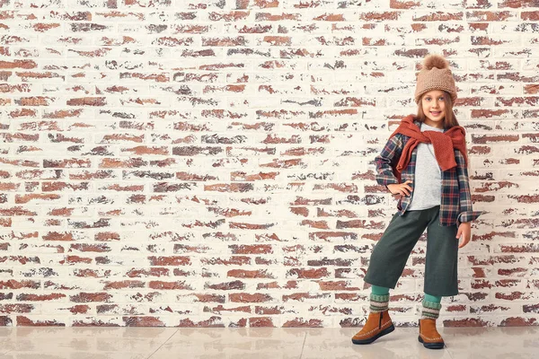 Fashionabla liten flicka i höst kläder nära tegelvägg — Stockfoto