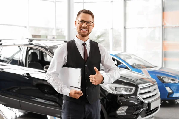 Salesman near car in modern salon — Stock Photo, Image