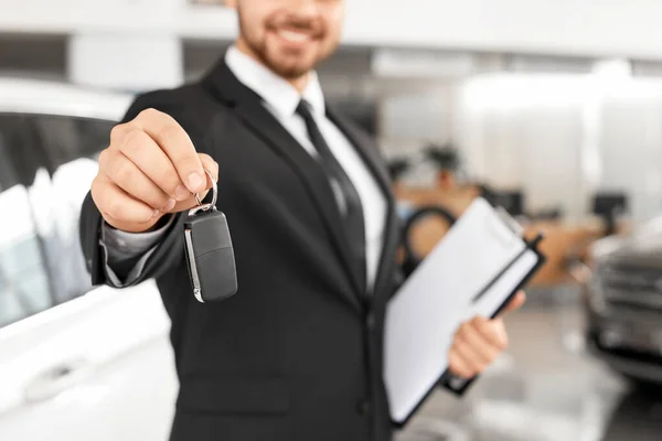 Salesman with car key in modern salon, closeup — Stock Photo, Image