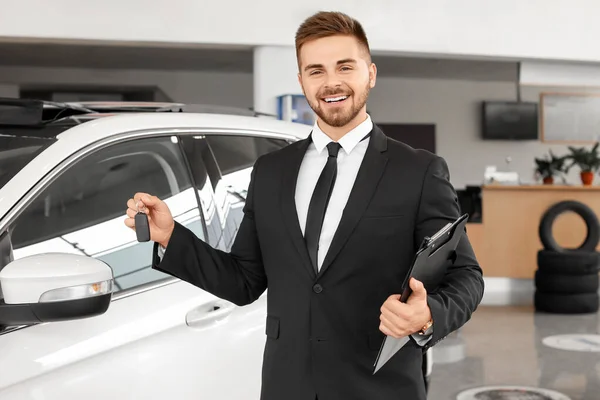 Salesman with car key in modern salon — Stock Photo, Image