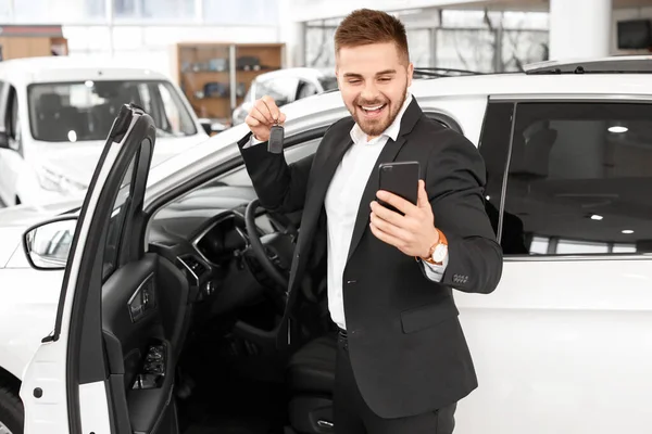 Happy male buyer near new car in salon — Stock Photo, Image