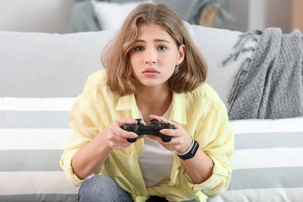 Sad teenager girl playing video games at home