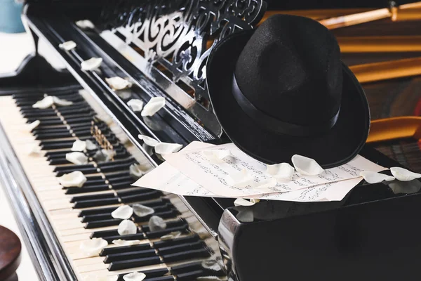 그랜드 피아노 위의 모자, 음표 종이 및 장미꽃 꽃잎 — 스톡 사진
