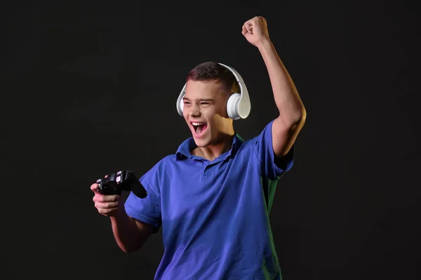 Happy teenager boy with game pad on dark background — Stock Photo, Image