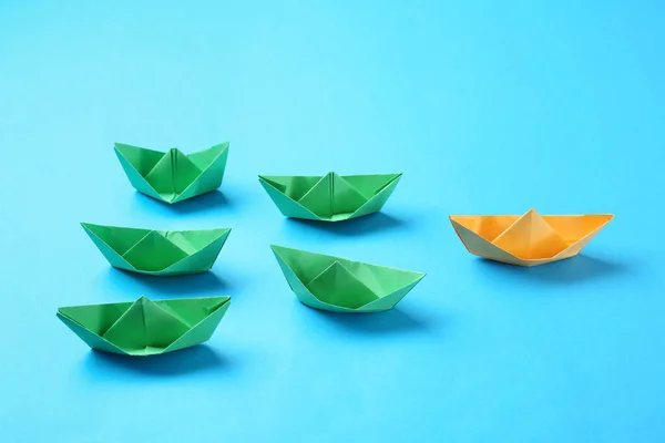 Πορτοκαλί origami βάρκα μεταξύ των πράσινων σε φόντο χρώμα. Έννοια της μοναδικότητας — Φωτογραφία Αρχείου