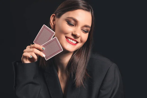 Krásná mladá žena s hracími kartami na tmavém pozadí — Stock fotografie
