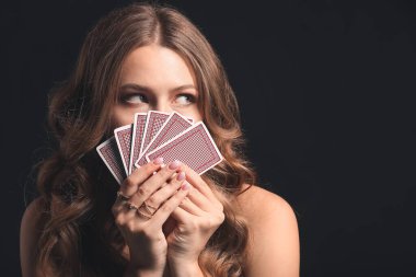 Koyu arkaplanda oyun kartları olan güzel bir genç kadın.