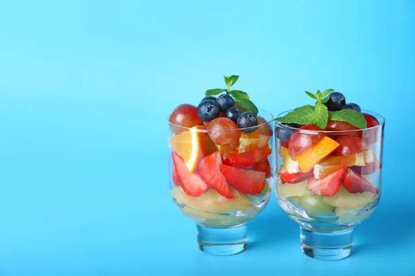 Gafas con sabrosa ensalada de frutas sobre fondo de color —  Fotos de Stock