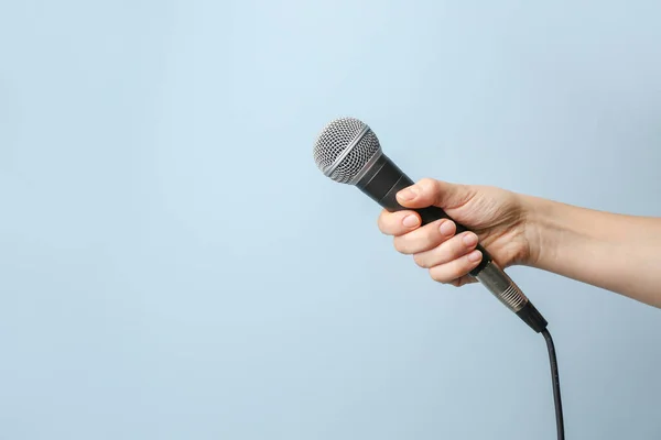 Main féminine avec microphone sur fond couleur — Photo