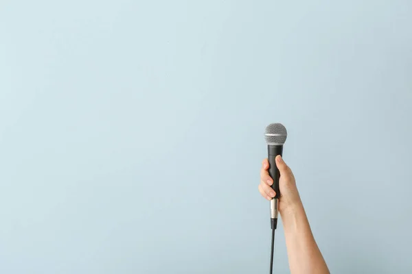 Female hand with microphone on color background