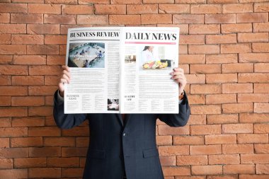 Duvara gazete dayamış yakışıklı bir iş adamı.