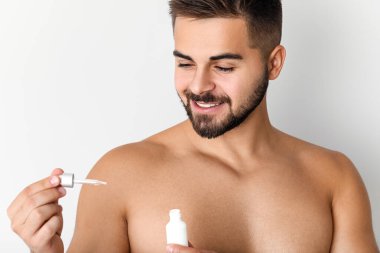 Hafif arka planda kozmetik ürünü olan yakışıklı bir genç.