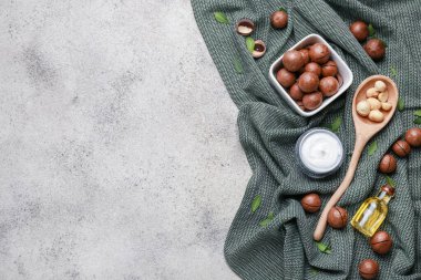 Gri arka planda yağlı ve kozmetik kremalı Macadamia fındıkları