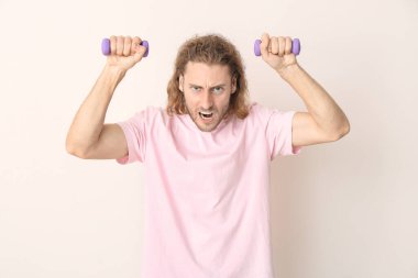 Hafif arka planda halterleri olan kızgın bir adamın portresi.
