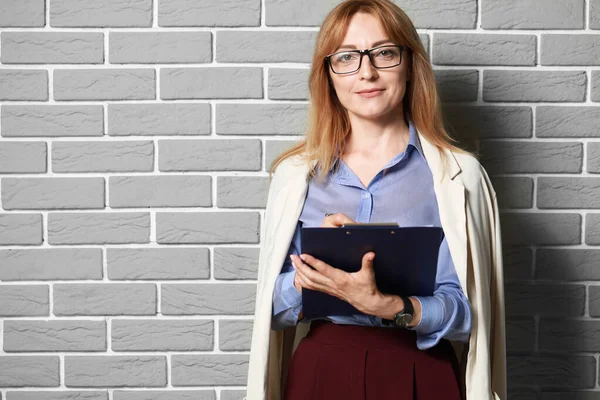 Portrait of stylish mature businesswoman near brick wall — Stock Photo, Image