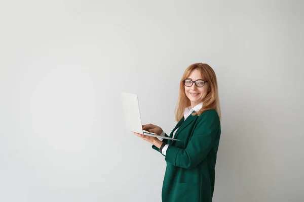 Portrait of stylish mature businesswoman with laptop on light background — Stock Photo, Image