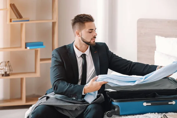 Young man packing things for business trip at home — Stock Photo, Image