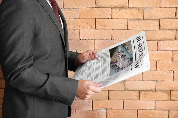 Hombre de negocios guapo con periódico contra pared de ladrillo — Foto de Stock