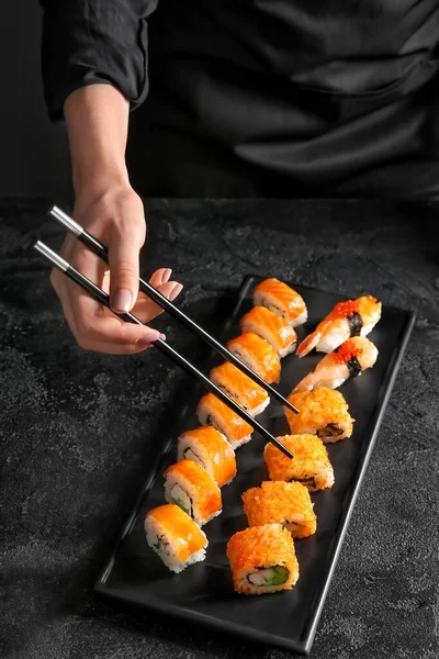 Frau isst schmackhaftes Sushi auf dunklem Hintergrund — Stockfoto