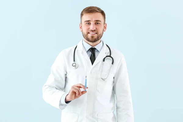 Doktor s injekční stříkačkou na světlém pozadí — Stock fotografie