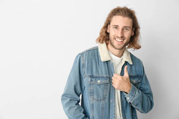 Portrait of handsome man showing thumb-up gesture on light background — Stock Photo, Image