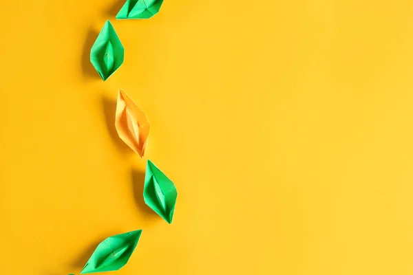 Barco de origami laranja entre os verdes no fundo de cor. Conceito de singularidade — Fotografia de Stock