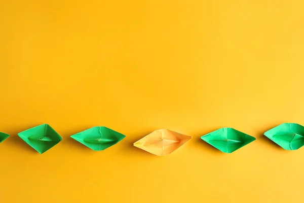 Oranje origami boot tussen groene op kleur achtergrond. Uniek begrip — Stockfoto