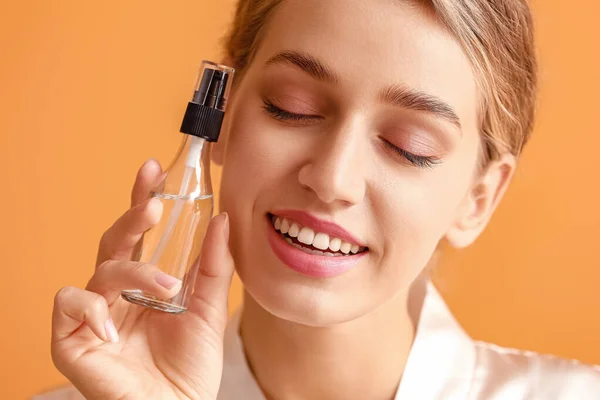 Hermosa mujer joven con producto cosmético sobre fondo de color — Foto de Stock