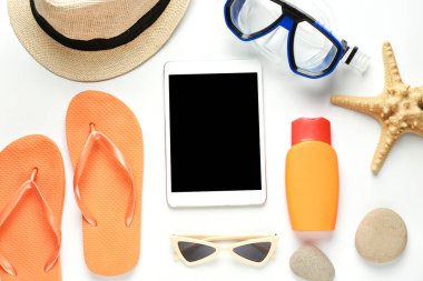 Beyaz arkaplanda plaj aksesuarları ve tablet bilgisayarlı kompozisyon