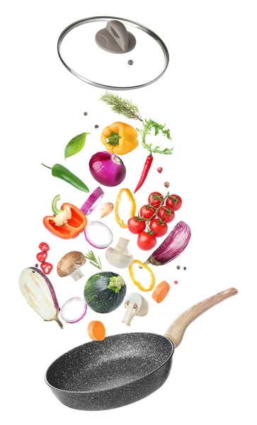 Frying pan and flying vegetables on white background