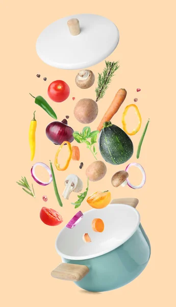 Saucepan and flying vegetables on color background