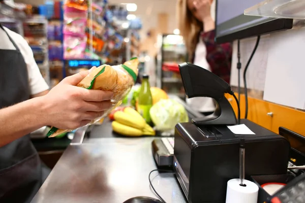 Male cashier checking out goods in supermarket — ストック写真