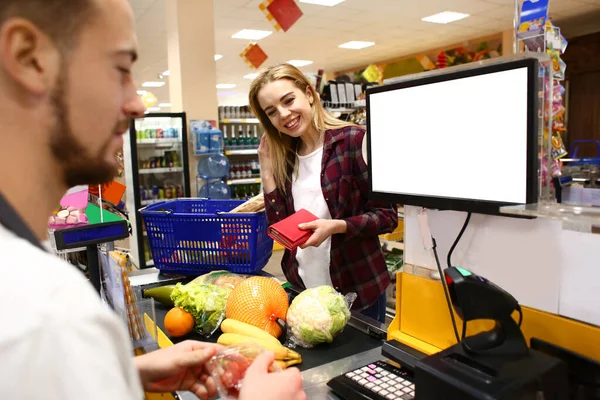 Junge Frau bezahlt Waren im Supermarkt — Stockfoto