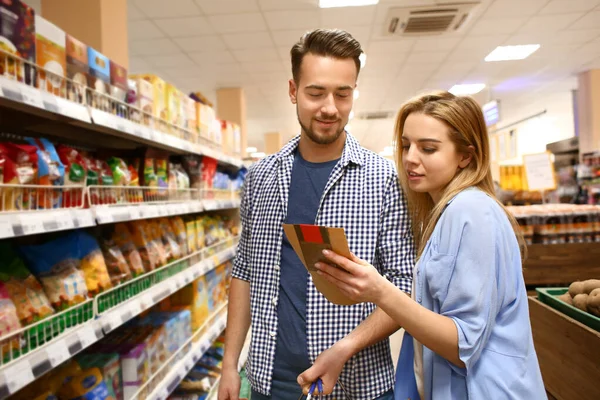 Mladý pár vybírá jídlo v supermarketu — Stock fotografie