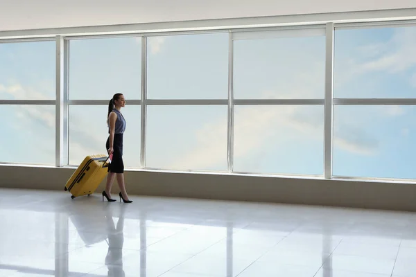 Havaalanı koridorunda bavullu genç bir iş kadını. — Stok fotoğraf