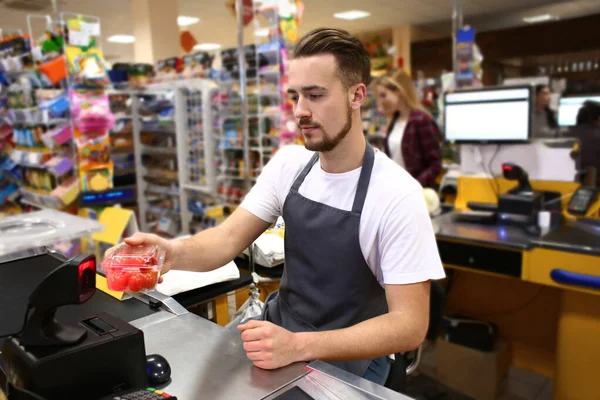 Male cashier checking out goods in supermarket — ストック写真